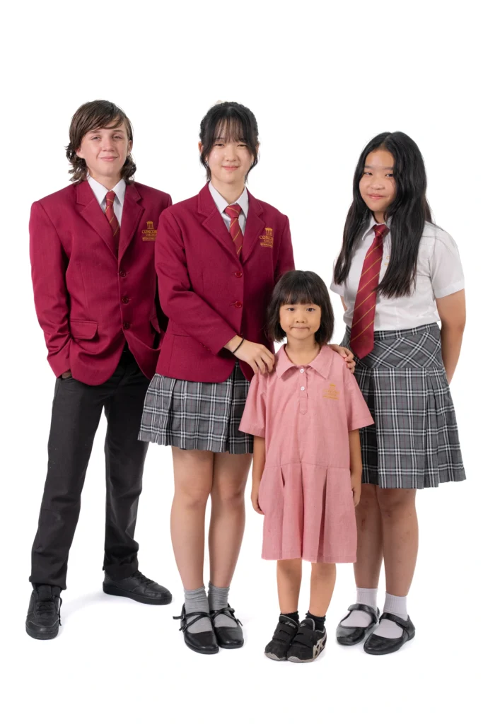 Four Concord College students in school uniform standing together against a plain background.