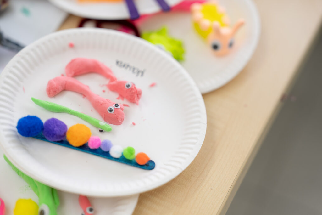 A close-up of two paper plates with colorful play-dough creations on them.