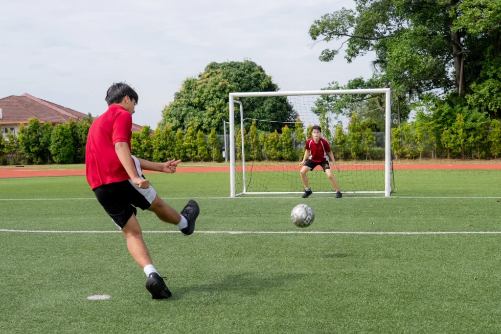 Students play football on the outdoor pitch.