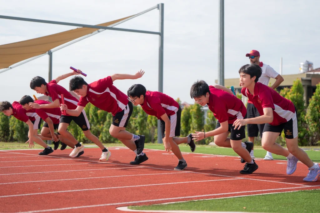 Students push off the blocks at the start of a race on the running track.
