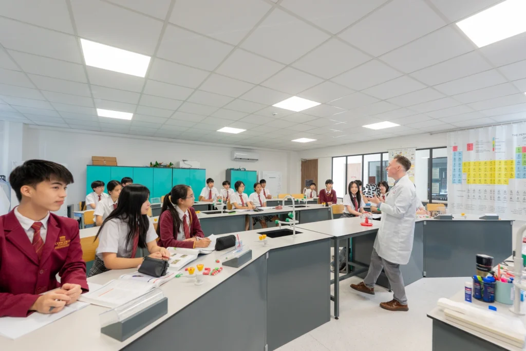 A chemistry teacher holds up a molecular model to a class of Secondary students.