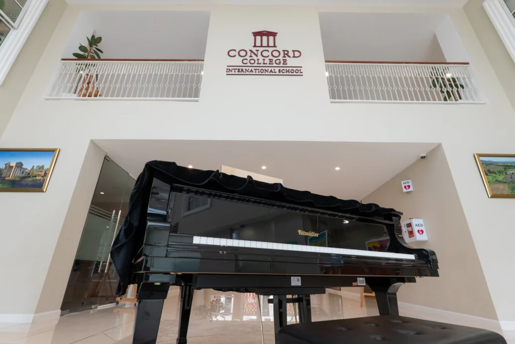 The grand piano in the main hall foyer beneath the Concord College International School crest.
