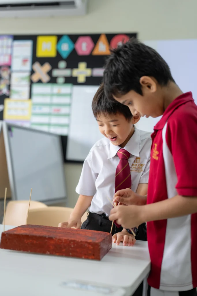 Two Year 3 pupils build a structure together during a hands-on lesson.